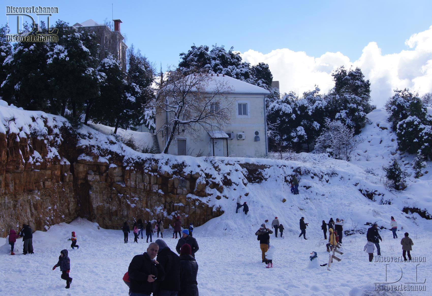House in Annaya under snow, people playing in snow